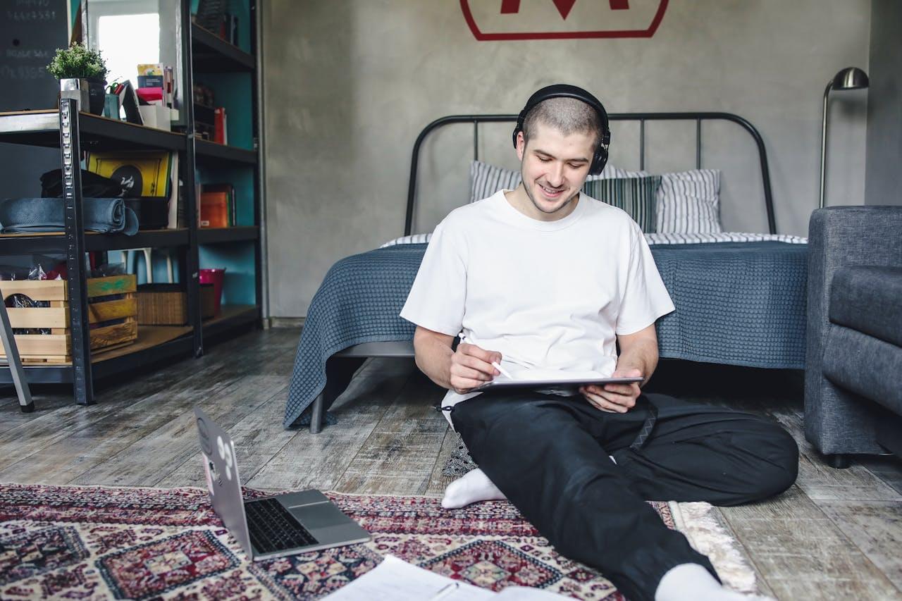 Парень смотрит в экран планшета с улыбкой